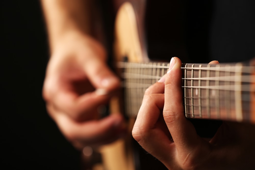 Due mani in primo piano che suonano la chitarra