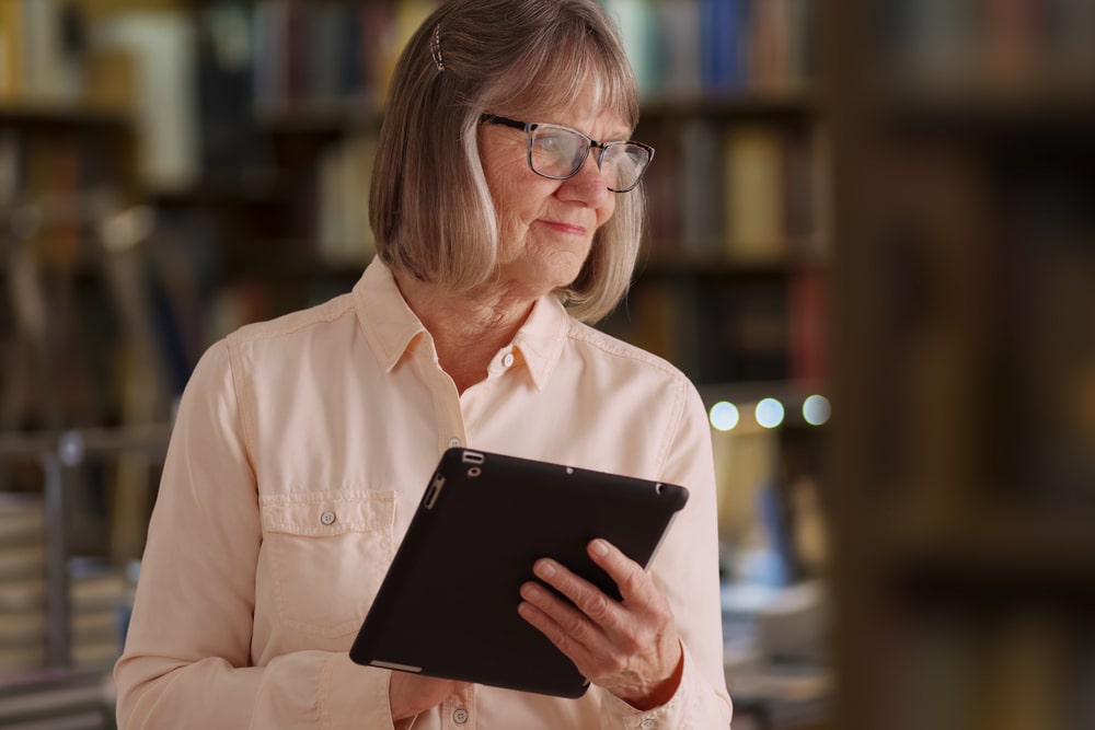 Una donna in biblioteca con un tablet in mano