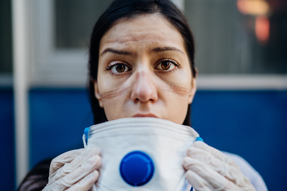 Una dottoressa esausta si toglie la mascherina