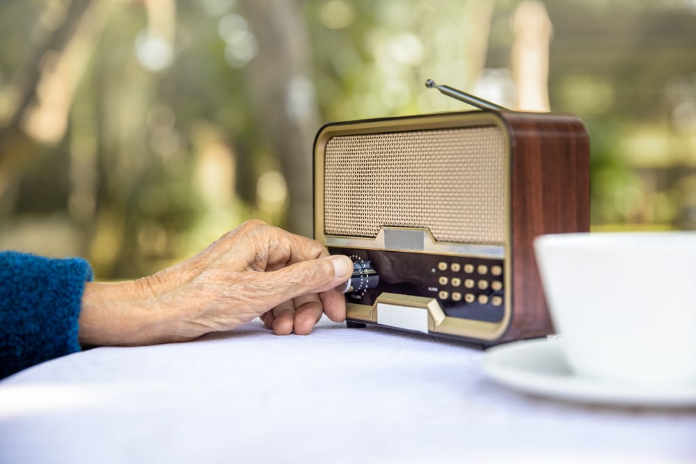 Una mano anziana regola il volume della radio