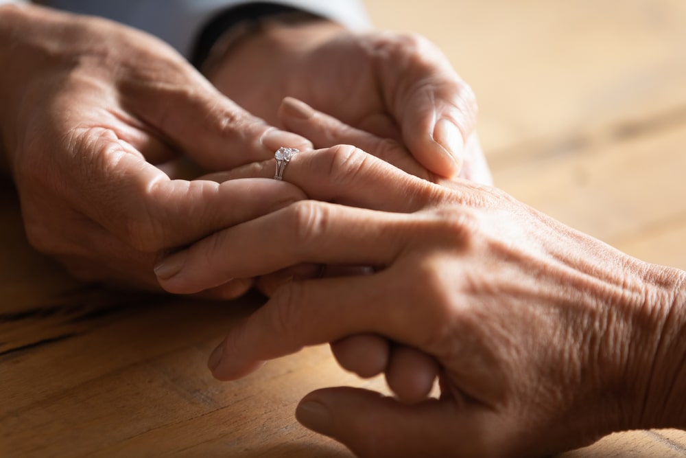 Un uomo infila un anello al dito di una donna