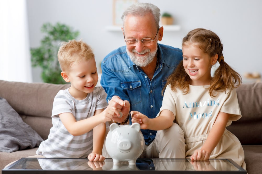 Un nonno con i nipoti mette monete nel salvadanaio
