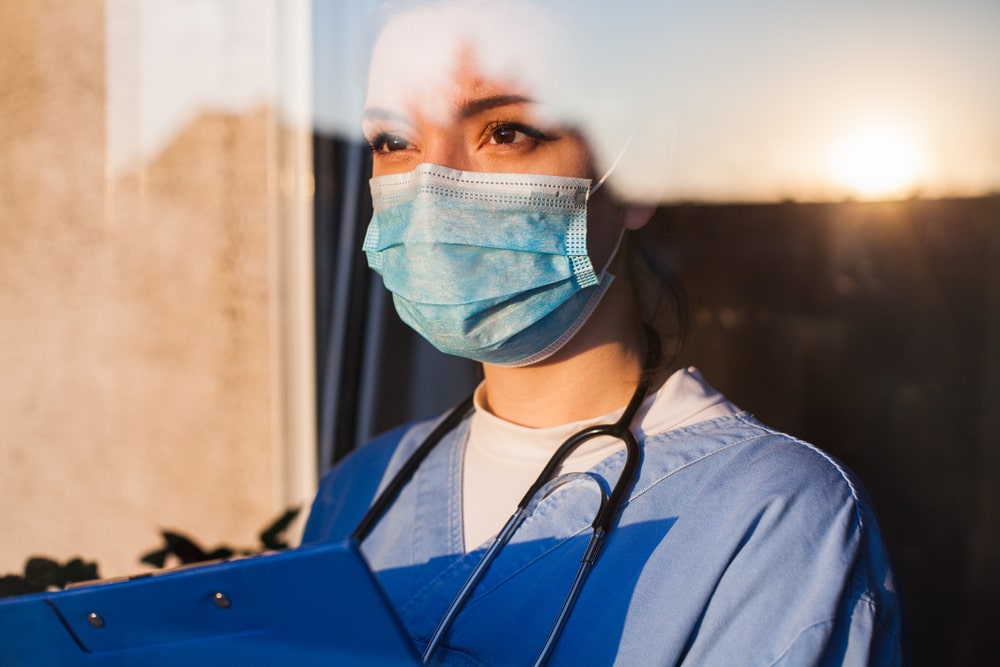 Un'infermiera guarda il tramonto dalla finestra