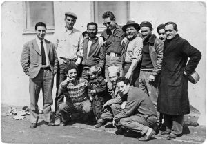 Charlton Heston (al centro) durante una pausa delle riprese del film. Alla sua destra si riconoscono Attilio Marra (guidatore del carro di Cipro) e JoeCanutt (controfigura di Heston). Alla sua sinistra Otello Capanna (guidatore del carro di Cartagine) e Sergio Casadei (guidatore del carro di Atene). In basso l’addestratore Pietro Marra con il piccolo Fraser, figlio di Charlton Heston. (Archivio Marra)