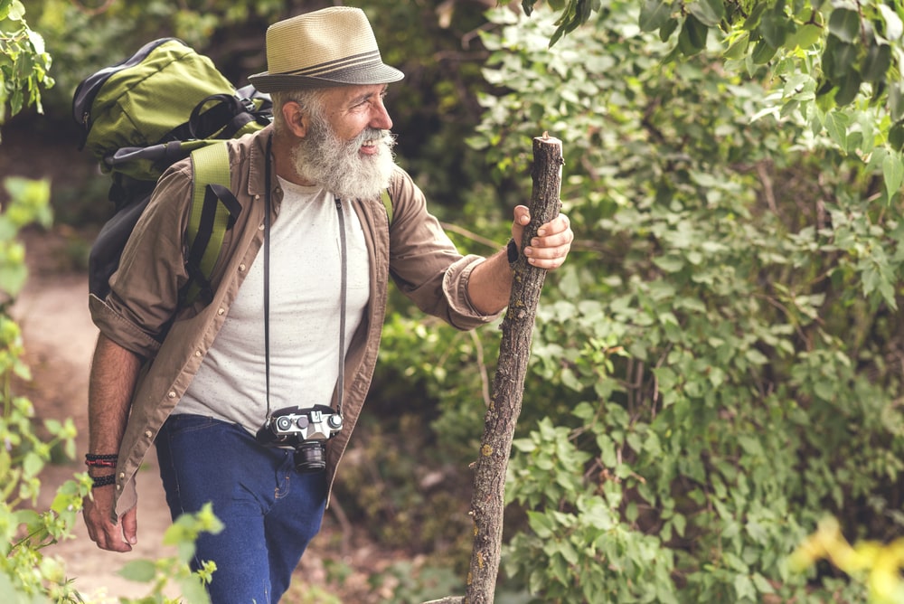 senior che cammina nel bosco con uno zaino